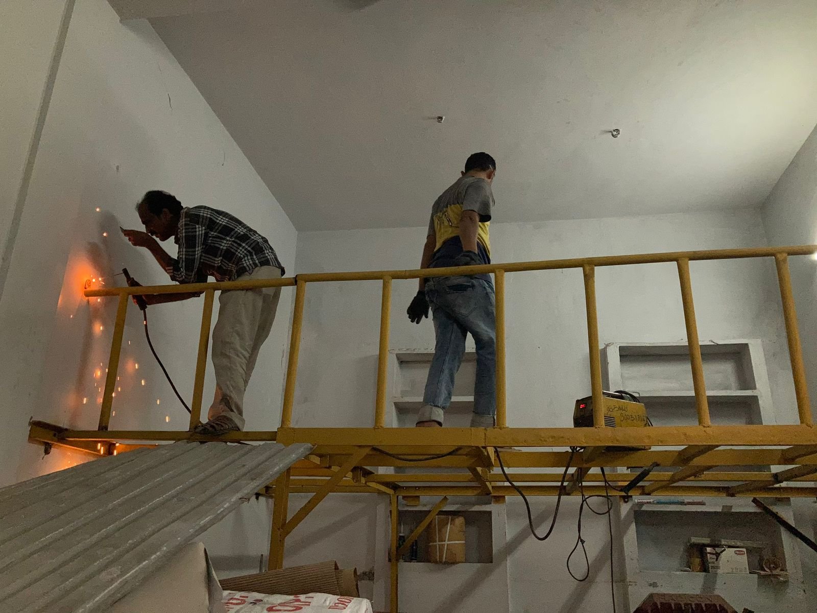 Fabrication team installing a custom metal staircase structure indoors